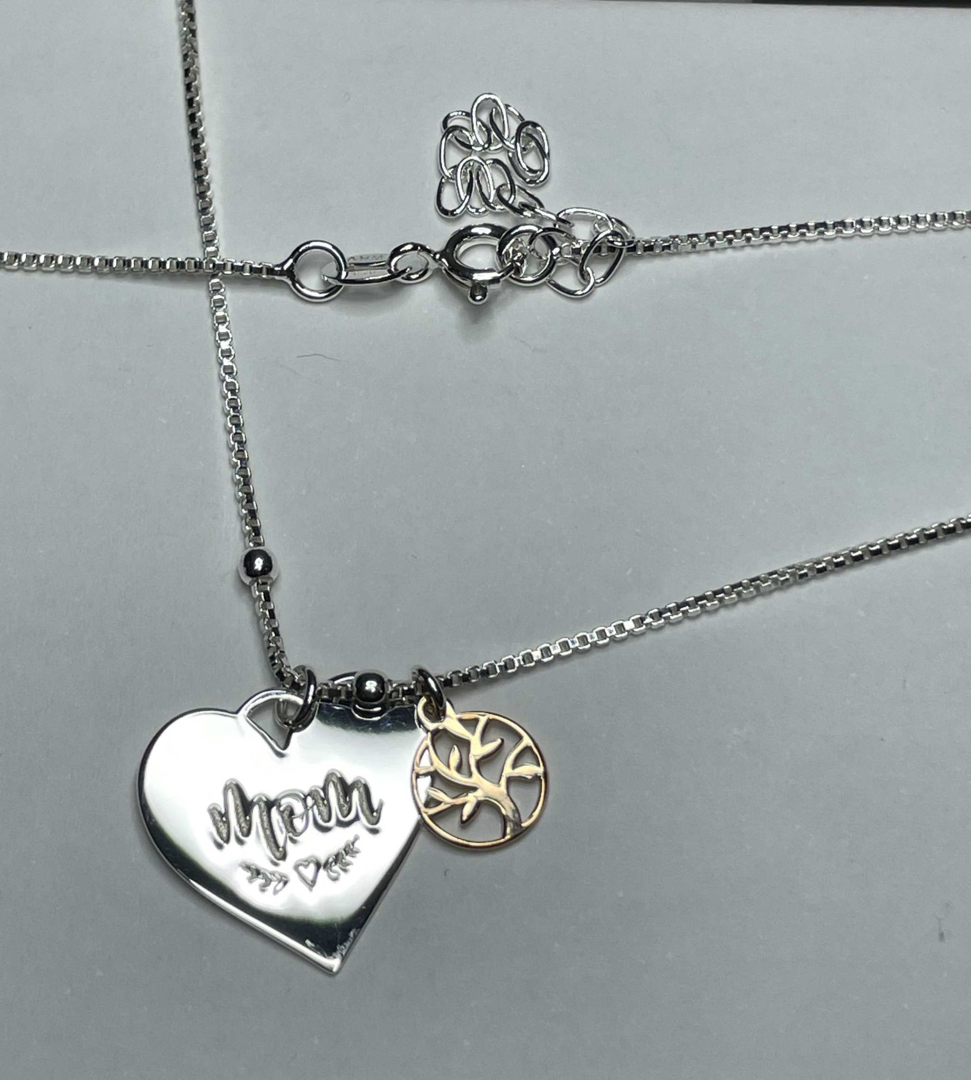 Sterling silver heart and family tree necklace for mom, featuring "mom" etching and rose gold-plated charm.